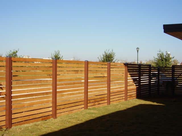 Wood slatted fence with horizontal boards with even consistent spacing