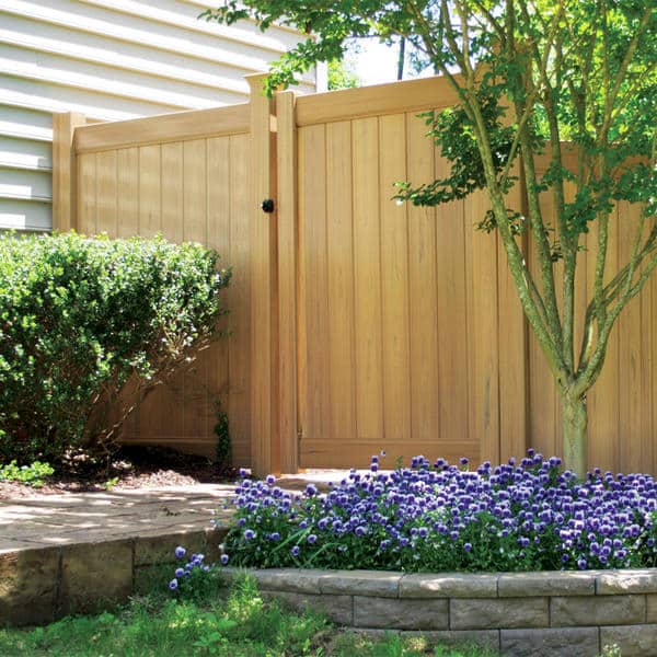 Wood fence and gate on a backyard of a Central Texas home with a planter-type made out of bricks holding purple flowers