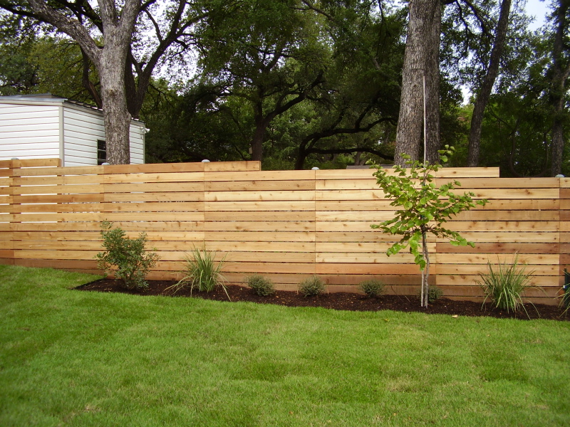 Horizontal wood fence with drops on a slightly sloped backyard in a Central Texas home