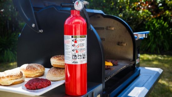 Grill with fire extinguisher and hamburger buns and patties