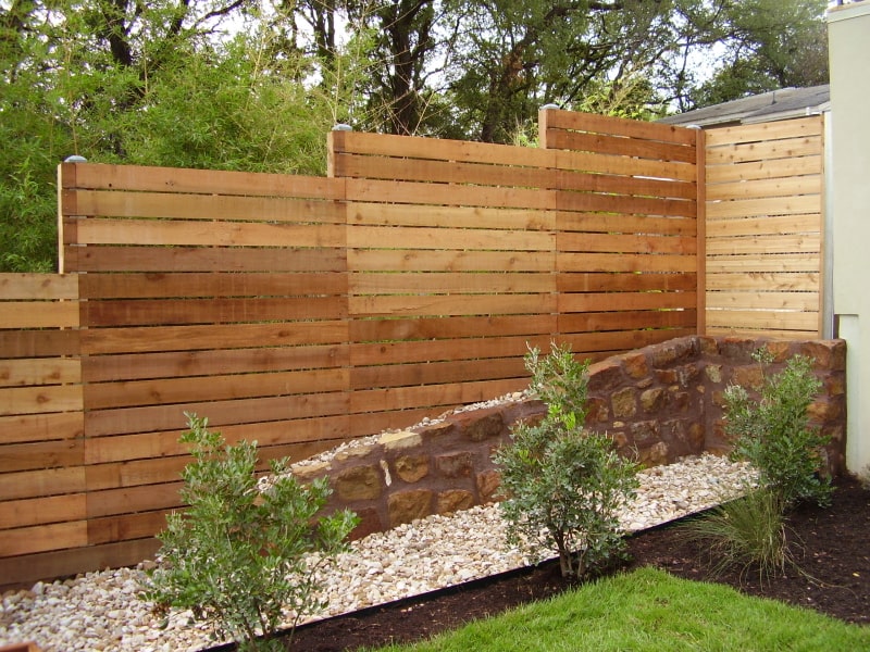 Horizontal wood fence on a slope yard with metal posts