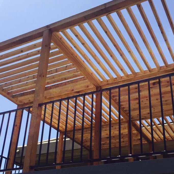 Open top wood pergola with slats placed in horizontal and vertical blocks viewed from the bottom
