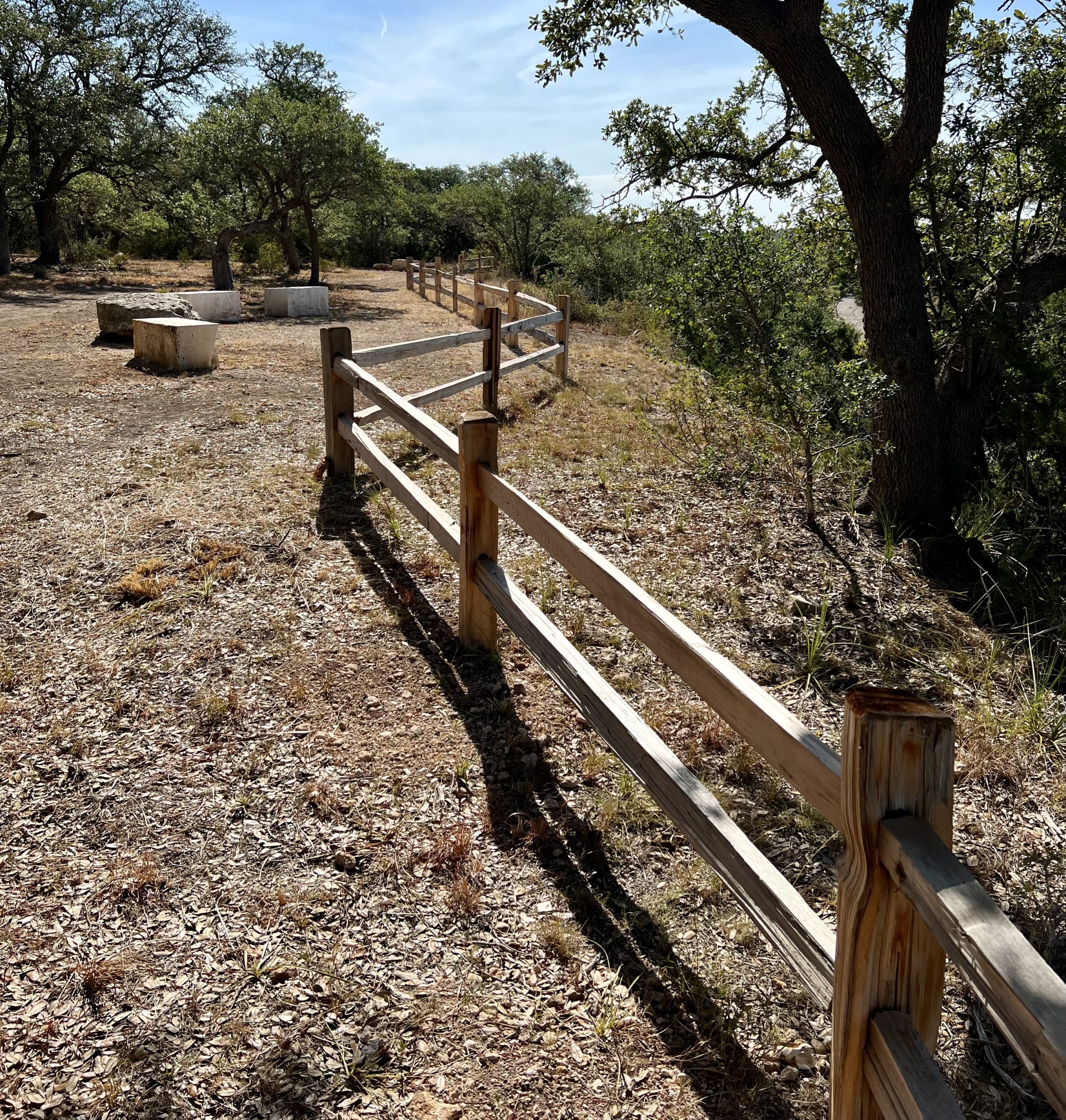 Rustic fence made out of logs place on a slight slope in a Central Texas ranch