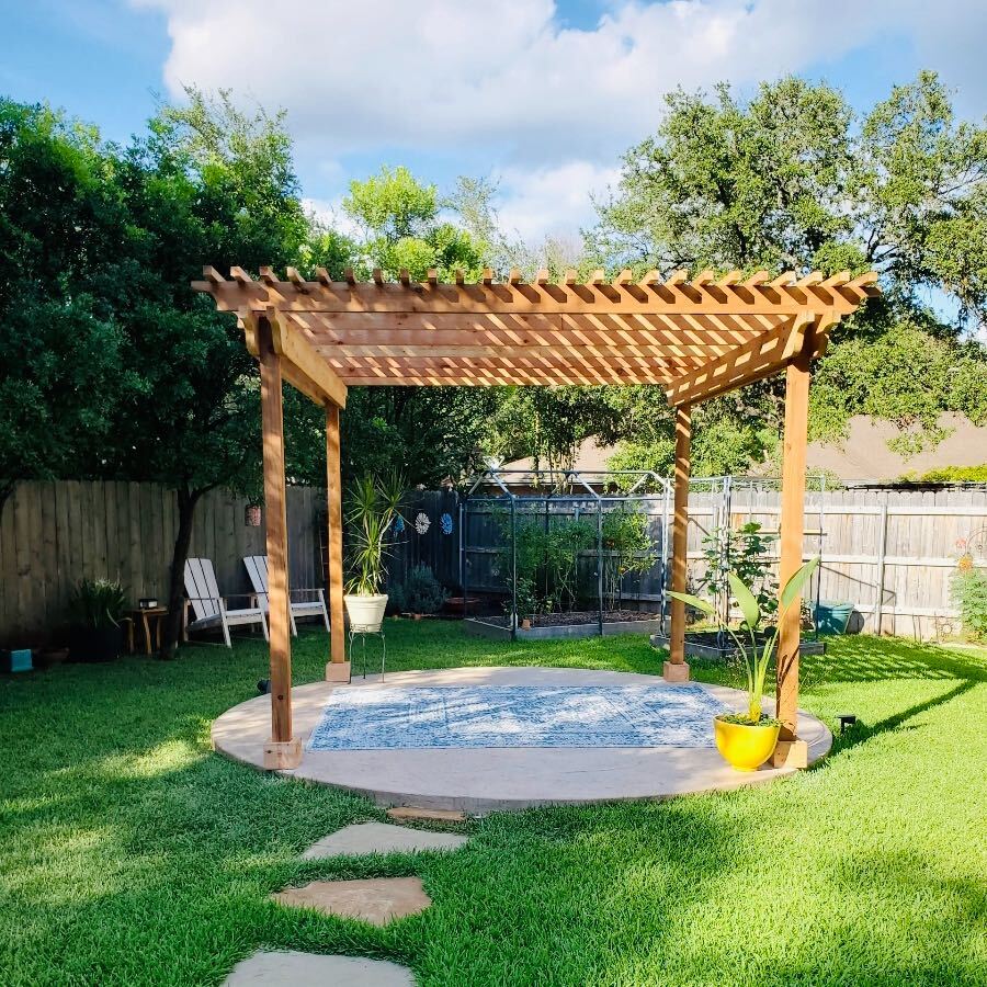 Wood pergola over two wood chairs and a table a rounded cemented area in the center of a backyard in Austin, Texas