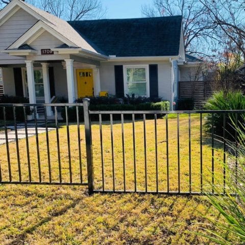 Three foot iron fence around the front yard of house with yellow door