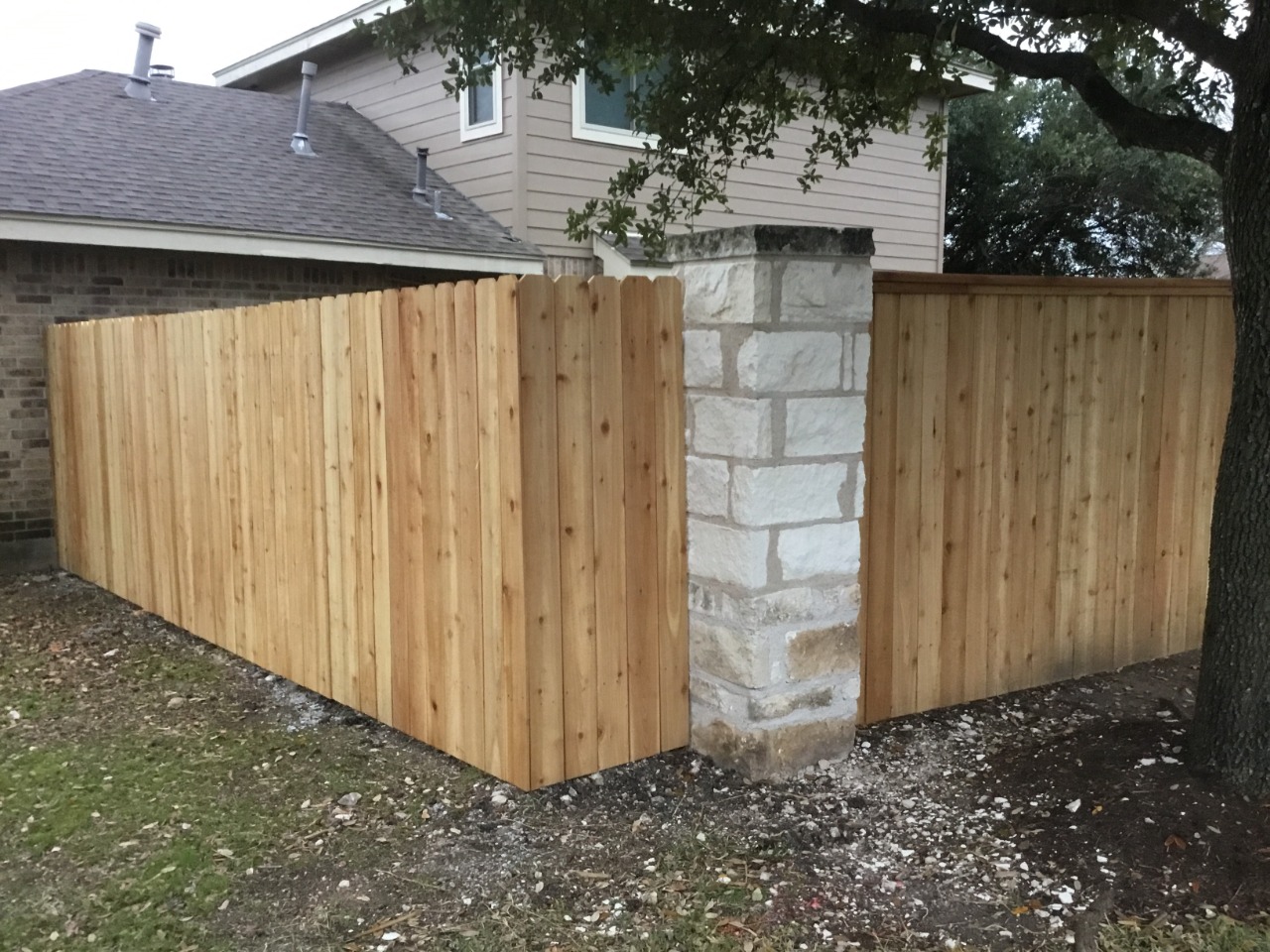 six foot privacy fence with cap and trim connected to stone pillars
