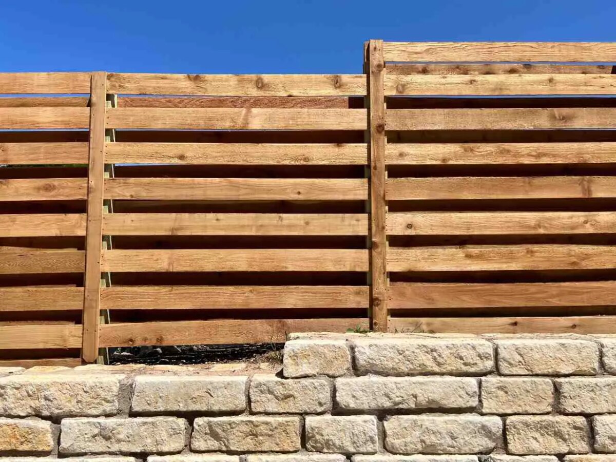 Horizontal shadow box fence stair stepping across top of stone