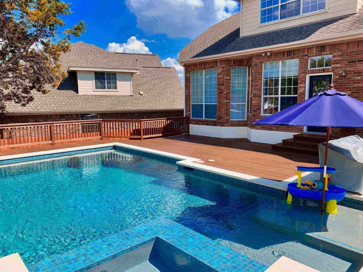 Stained composite deck around pool with cedar railing