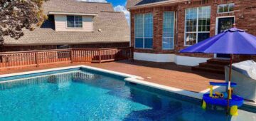 Stained composite deck around pool with cedar railing