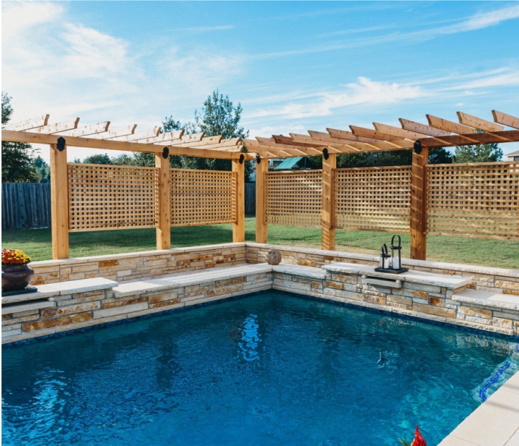 Lattice privacy fence surrounding one side of a pool