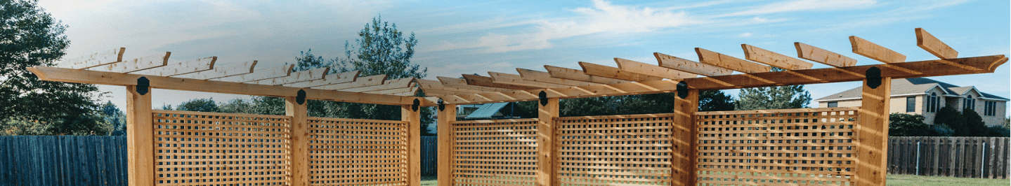 L-shaped wood pergola enclosing a part of a pool with a lattice screen for added privacy