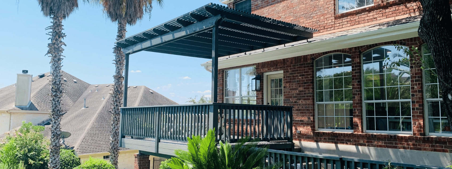 Teal colored patio cover over the deck of a second story brick house in Austin, Texas