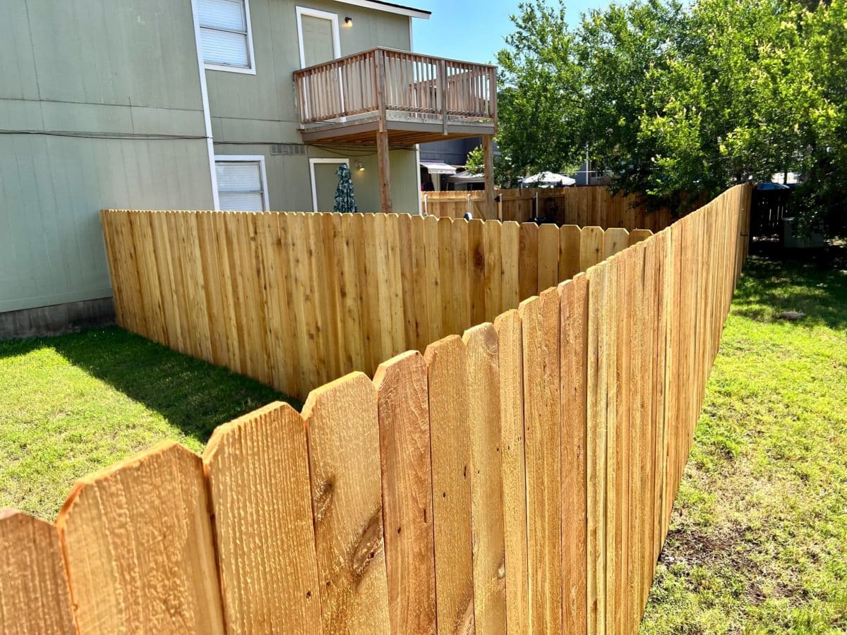Wood dog ear fence dividing backyards of neighboring apartments in Austin