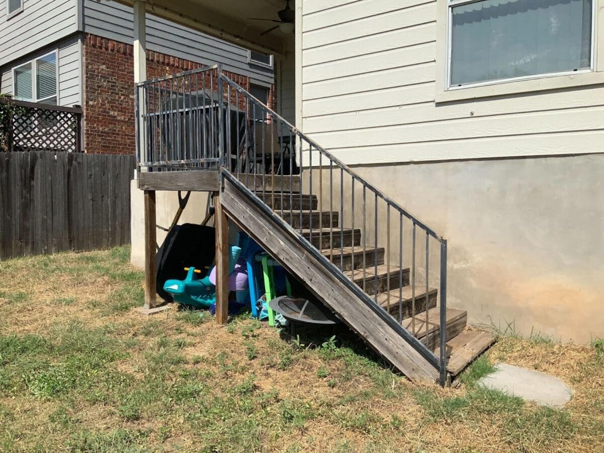 Before picture of poor condition of iron railings on wood stairs and deck