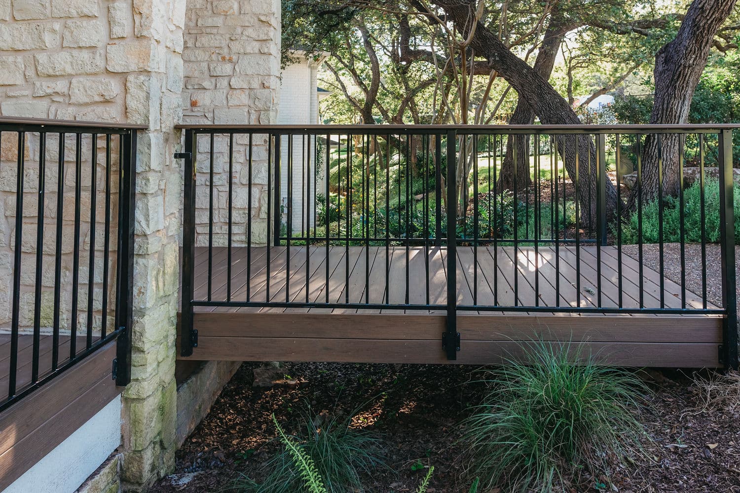 Side view of a light brown composite deck with iron deck railing