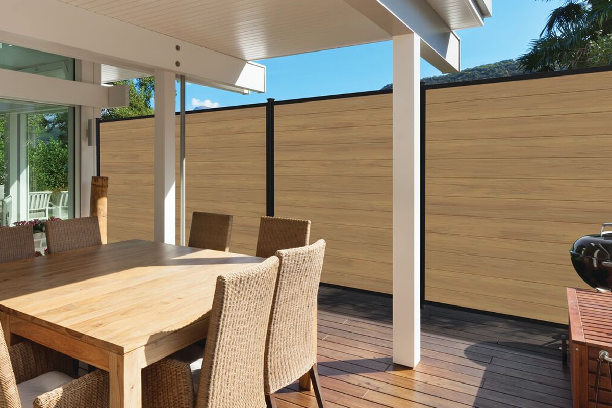 Sequoia vinyl fence in cypress color enclosing a an attached deck to a house that has a dining table