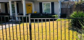 Three foot iron fence around the front yard of house with yellow door
